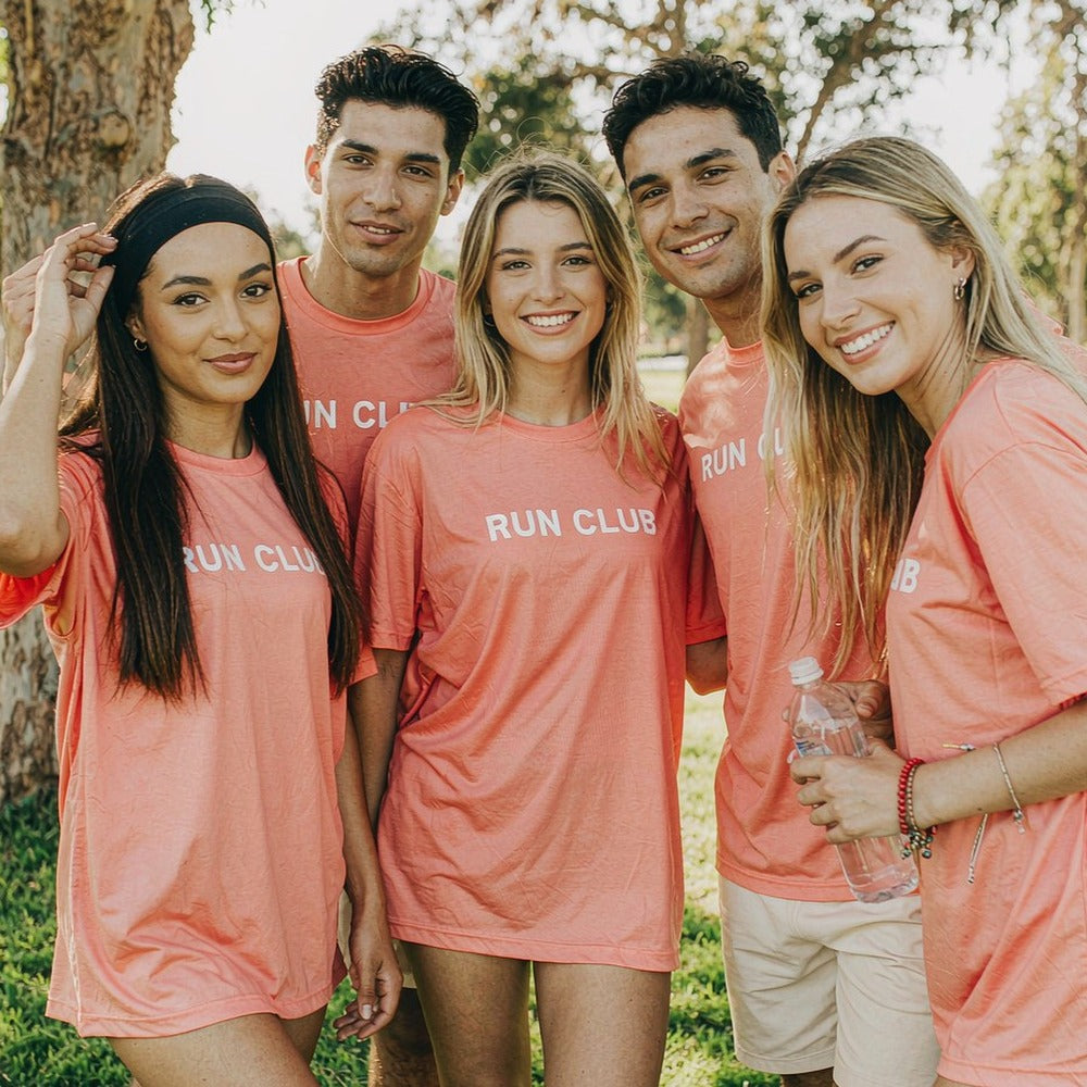Run club members in matching coral custom printed tees, smiling at the camera