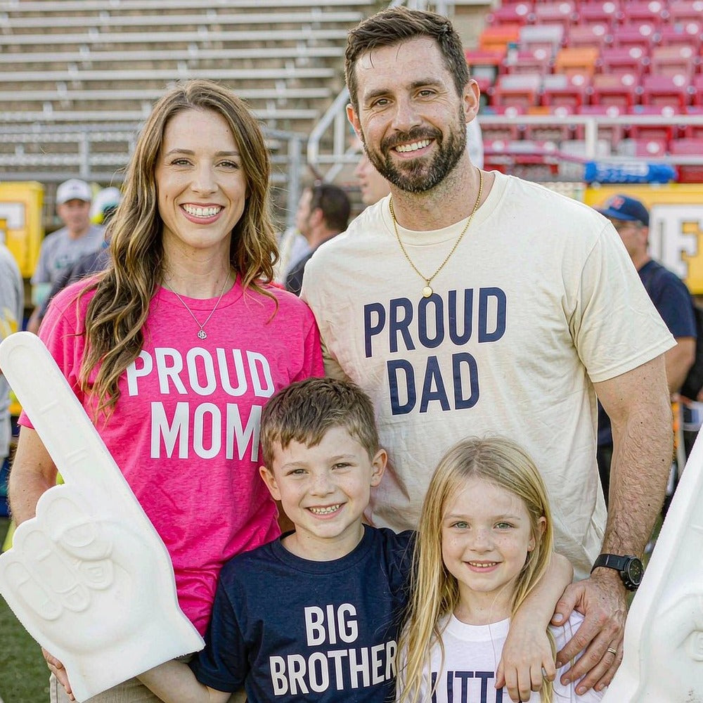 Family in matching PROUD MOM and PROUD DAD custom printed tees at a game