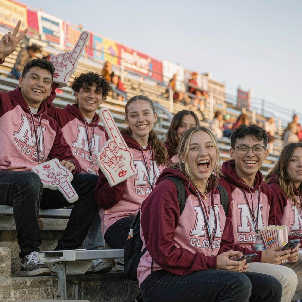 Students in matching custom printed hoodies celebrating together at a stadium