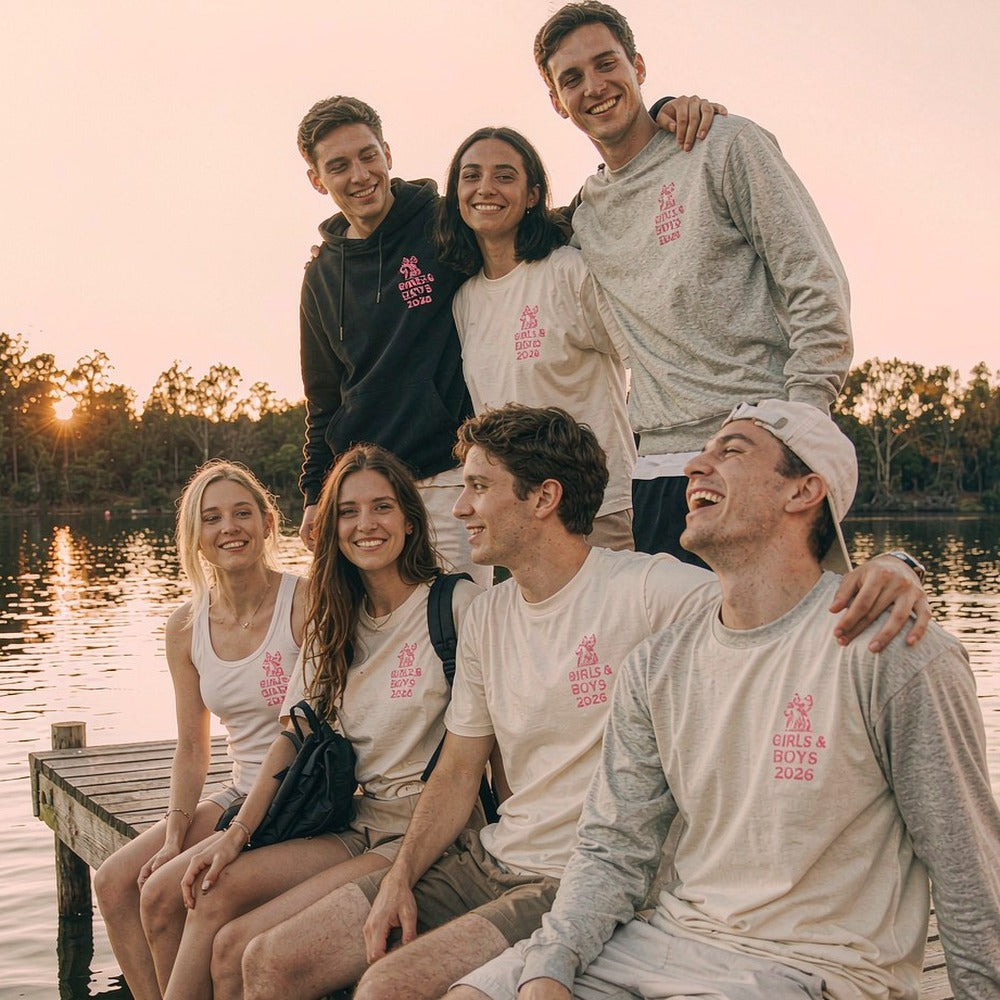 Friends reunited in matching custom printed tees by a lake at sunset